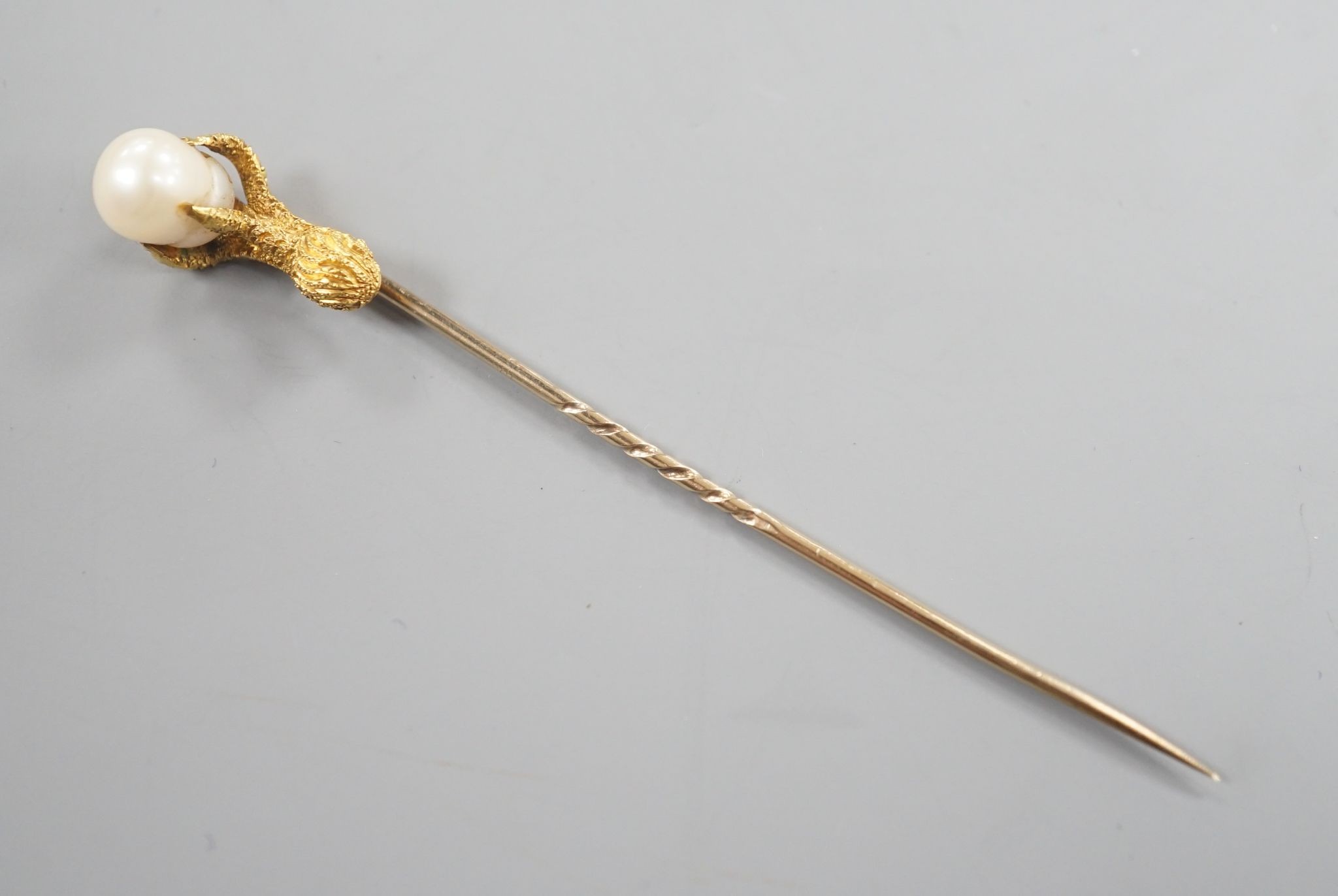 A 19th century yellow metal stick pin, the terminal modelled as an eagle's claw grasping a baroque pearl, 78mm, gross weight 3.3 grams, with box.